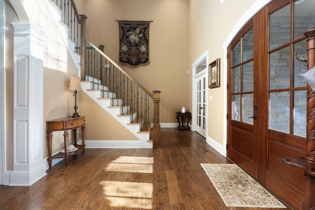 foyer entrance with a towering ceiling, dark hardwood / wood-style flooring, and french doors