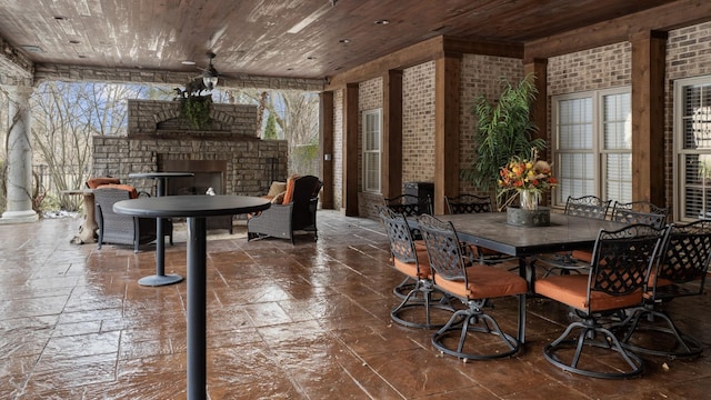 dining room with wooden ceiling, brick wall, an outdoor brick fireplace, and a healthy amount of sunlight