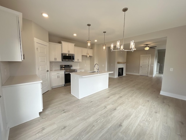 kitchen featuring white cabinetry, an island with sink, ceiling fan, stainless steel appliances, and sink