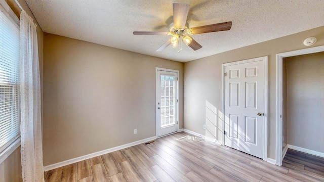 unfurnished bedroom with ceiling fan, multiple windows, and a textured ceiling