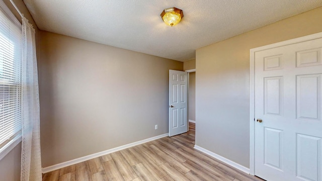 unfurnished bedroom with a textured ceiling and light wood-type flooring