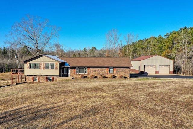 split level home featuring a front lawn, a garage, and an outbuilding