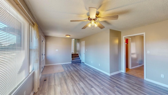 empty room featuring light wood-type flooring, ceiling fan, and a textured ceiling