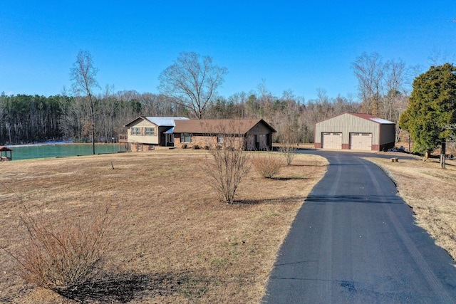 view of front of property with a garage, a front yard, and an outbuilding