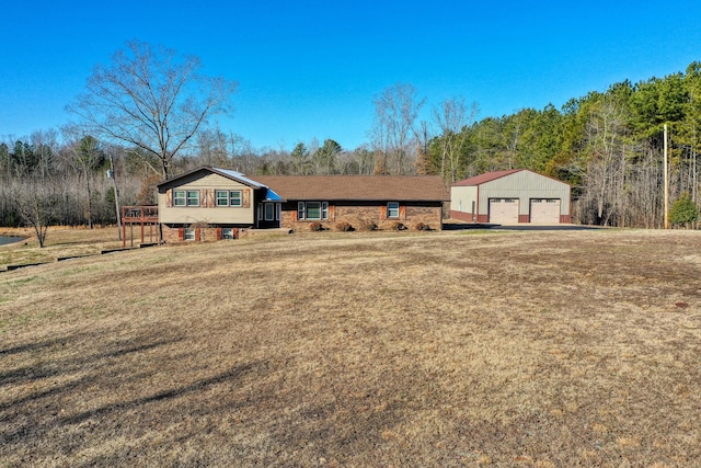 view of front of house featuring a garage, a front lawn, and an outbuilding