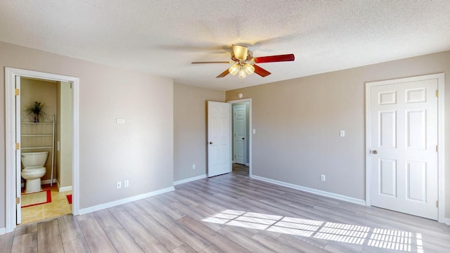 unfurnished bedroom with a textured ceiling, ceiling fan, ensuite bathroom, and light hardwood / wood-style flooring