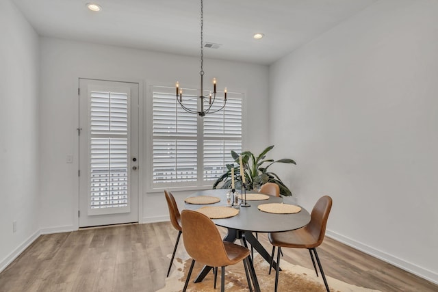 dining space with a notable chandelier and light hardwood / wood-style floors