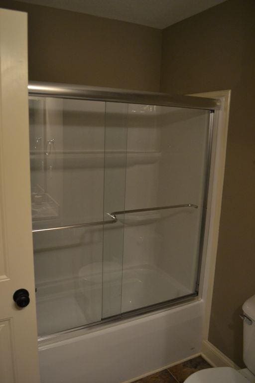 bathroom featuring toilet, tile patterned floors, and shower / bath combination with glass door