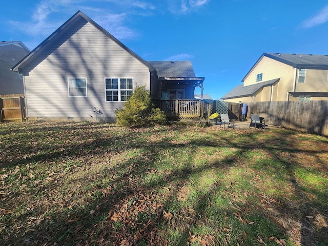 back of property with a lawn and a deck