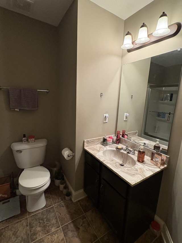 bathroom featuring an enclosed shower, vanity, and toilet