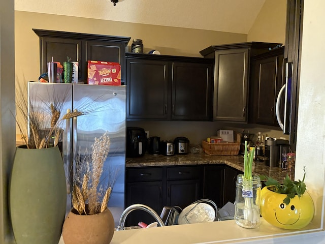 kitchen featuring lofted ceiling, appliances with stainless steel finishes, and dark brown cabinetry