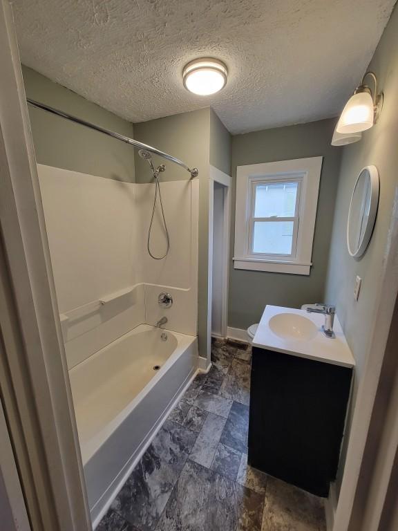 bathroom with shower / bathing tub combination, vanity, and a textured ceiling