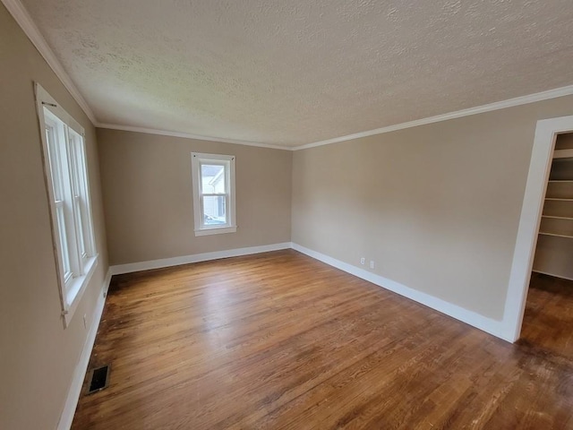 empty room with ornamental molding, a textured ceiling, and hardwood / wood-style floors