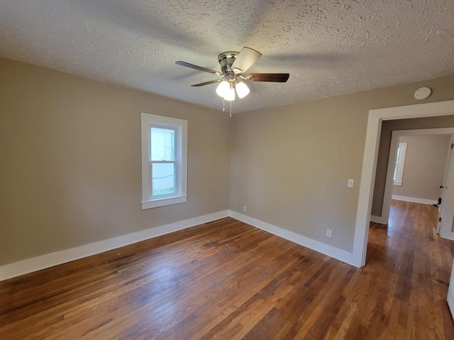 empty room with ceiling fan, dark wood-type flooring, and a textured ceiling