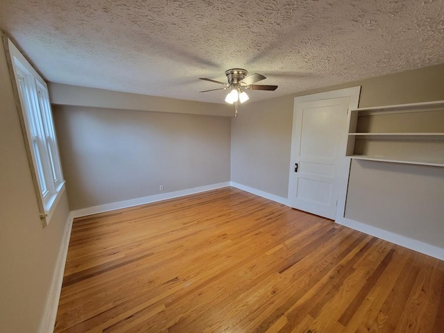 unfurnished bedroom with ceiling fan, a closet, light wood-type flooring, and a textured ceiling