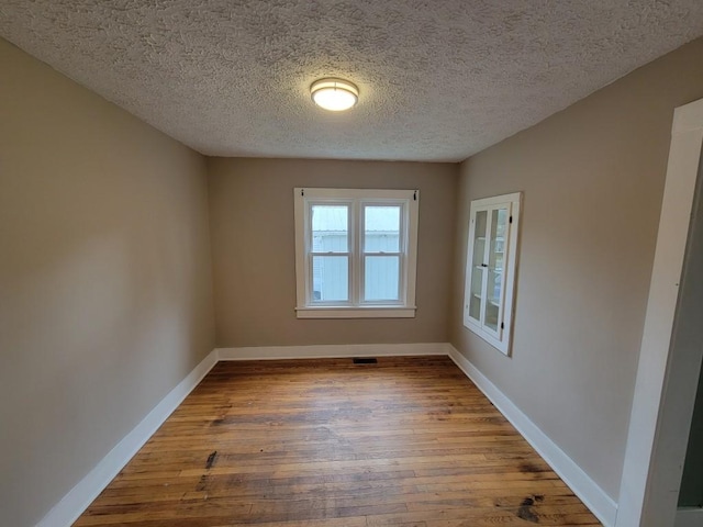 spare room featuring a textured ceiling and hardwood / wood-style flooring