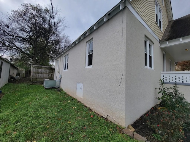 view of side of home featuring a lawn and cooling unit