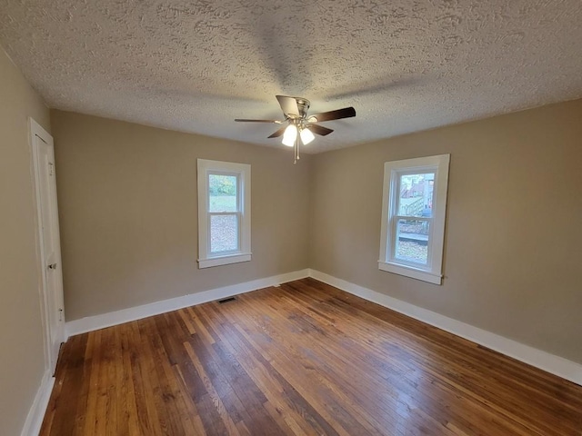 unfurnished room with ceiling fan, plenty of natural light, wood-type flooring, and a textured ceiling