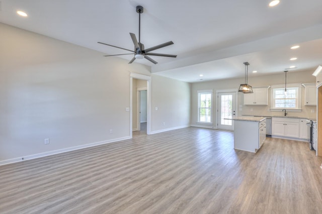 kitchen with white cabinets, a center island, appliances with stainless steel finishes, decorative light fixtures, and light hardwood / wood-style floors