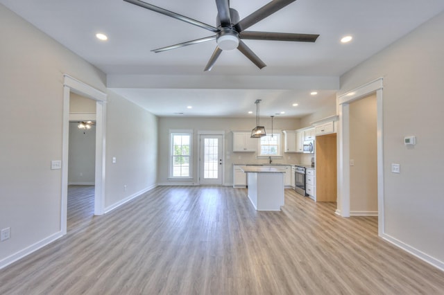 kitchen with ceiling fan, appliances with stainless steel finishes, decorative light fixtures, white cabinets, and a center island