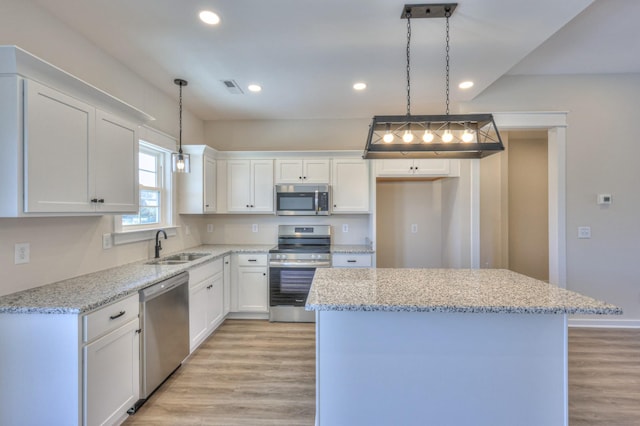 kitchen featuring decorative light fixtures, white cabinetry, a center island, and stainless steel appliances