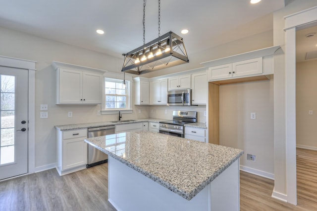 kitchen with white cabinets, pendant lighting, stainless steel appliances, and a kitchen island