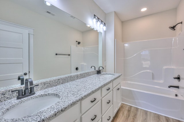 bathroom featuring hardwood / wood-style flooring, washtub / shower combination, and vanity