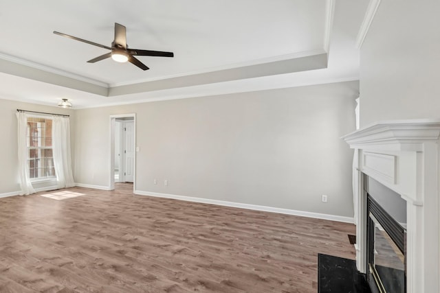 unfurnished living room featuring ceiling fan, hardwood / wood-style floors, crown molding, and a raised ceiling