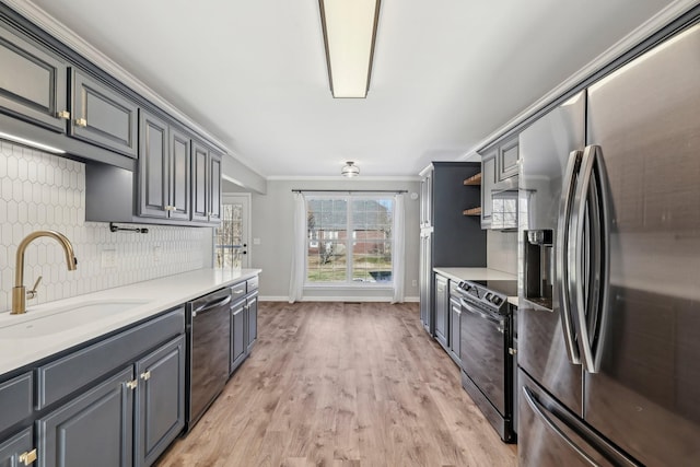 kitchen with appliances with stainless steel finishes, decorative backsplash, sink, gray cabinetry, and crown molding