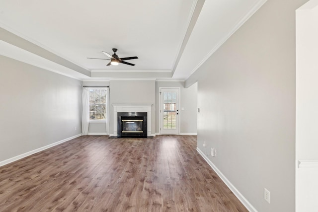 unfurnished living room with ceiling fan, a tray ceiling, ornamental molding, and a healthy amount of sunlight