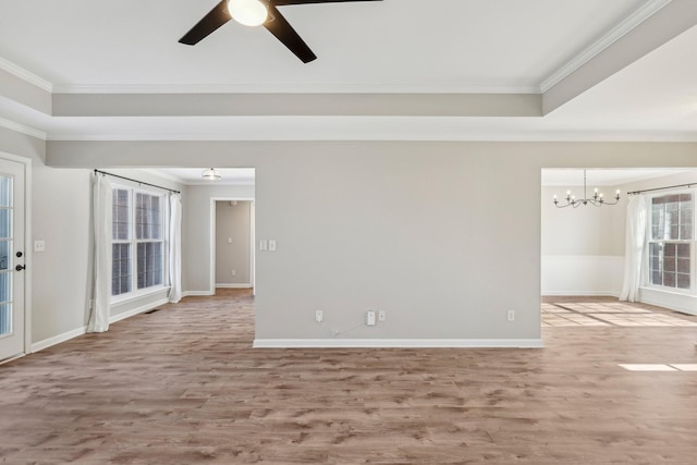 spare room featuring ceiling fan with notable chandelier, a tray ceiling, ornamental molding, and hardwood / wood-style flooring