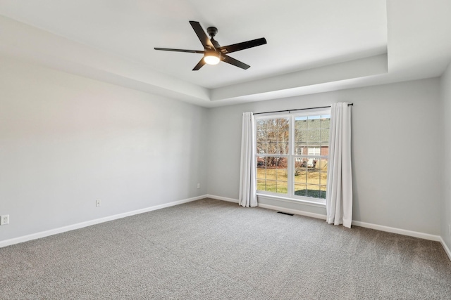 carpeted spare room featuring ceiling fan and a raised ceiling