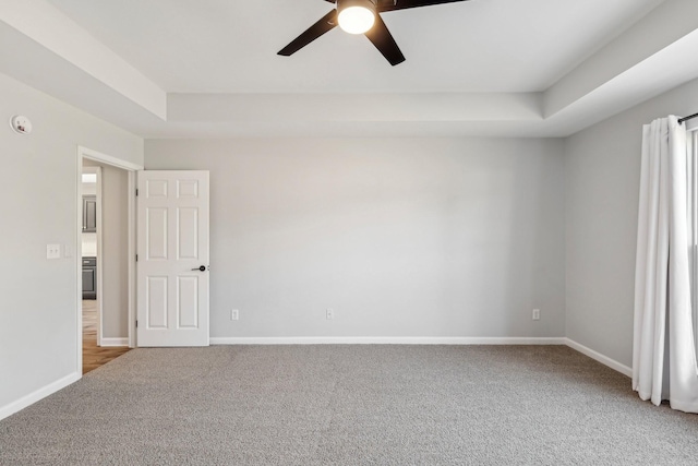 carpeted spare room featuring ceiling fan and a tray ceiling