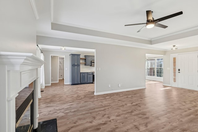 unfurnished living room with ceiling fan, wood-type flooring, and a raised ceiling