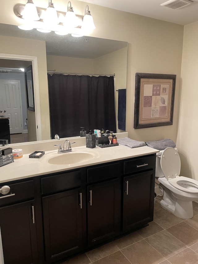 bathroom with toilet, vanity, and tile patterned flooring