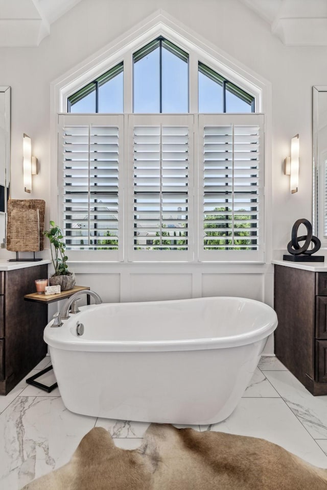 bathroom featuring a tub, vanity, and lofted ceiling