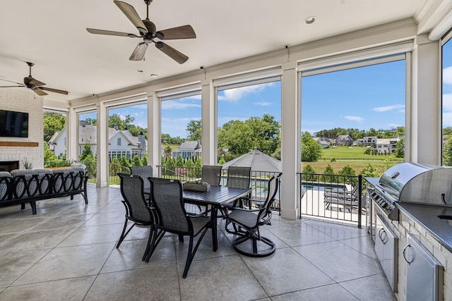 sunroom / solarium featuring ceiling fan, plenty of natural light, and an outdoor brick fireplace