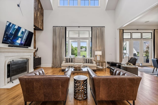 living room with light wood-type flooring, french doors, and a high ceiling