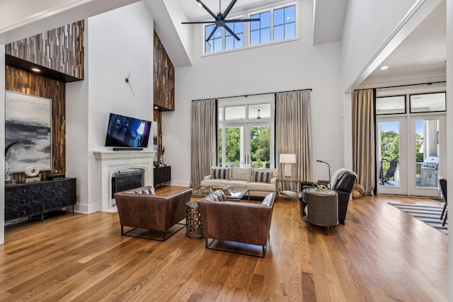 living room featuring french doors, a towering ceiling, and light hardwood / wood-style flooring