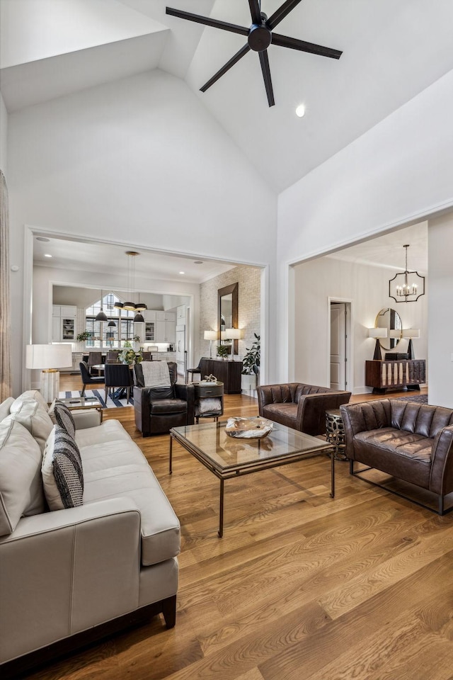 living room featuring high vaulted ceiling, hardwood / wood-style floors, and ceiling fan with notable chandelier