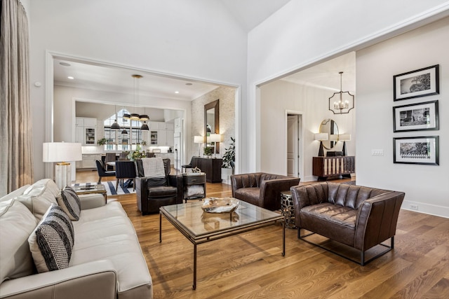 living room featuring a towering ceiling, hardwood / wood-style floors, and a notable chandelier