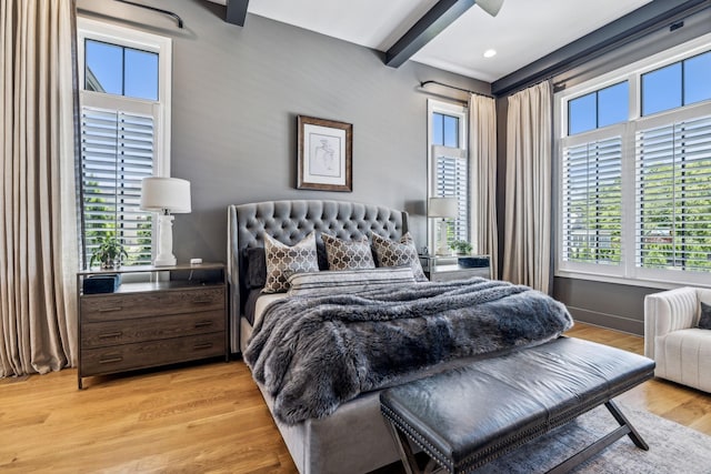 bedroom featuring ceiling fan, light hardwood / wood-style floors, and beamed ceiling