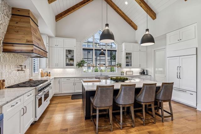 kitchen with premium range hood, white cabinetry, premium appliances, tasteful backsplash, and hanging light fixtures