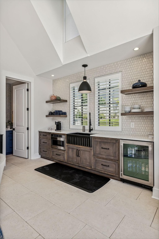 bar with wine cooler, sink, hanging light fixtures, light tile patterned flooring, and dark brown cabinets