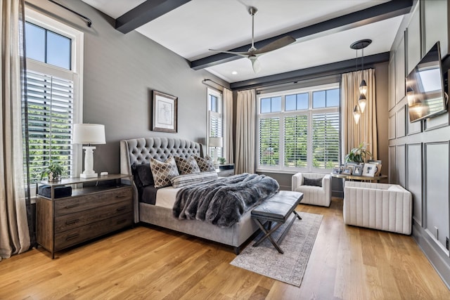 bedroom with ceiling fan, beamed ceiling, and light wood-type flooring