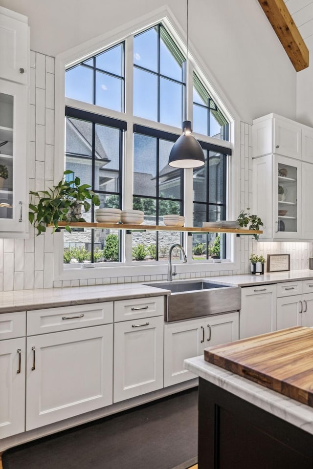 kitchen with sink, white cabinets, and beam ceiling