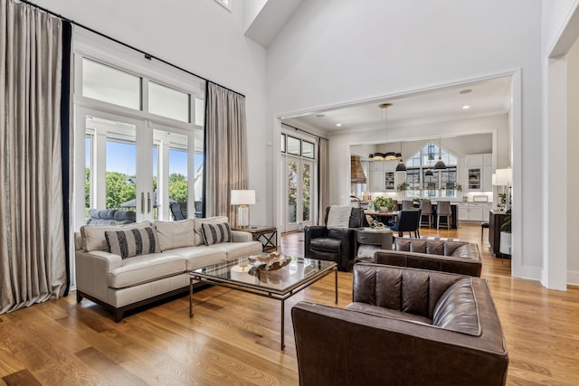 living room with light wood-type flooring, french doors, and a towering ceiling