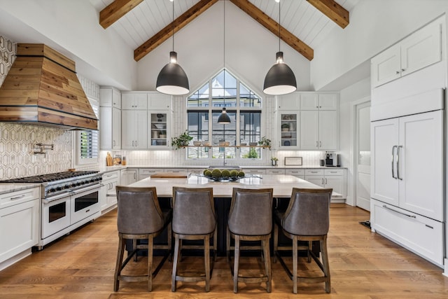 kitchen featuring premium appliances, white cabinets, and custom exhaust hood