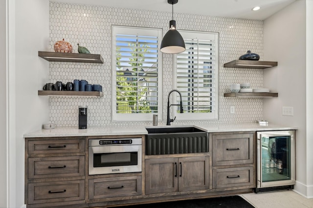 bar featuring dark brown cabinetry, wine cooler, sink, hanging light fixtures, and stainless steel oven