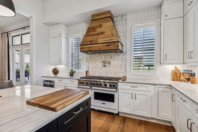 kitchen with backsplash, white cabinets, custom range hood, and stainless steel appliances